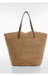 Detailed macro view of woven geometric patterns on a large straw tote bag with brown handles