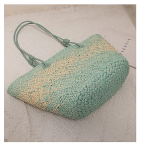 Close-up of mint green and beige woven straw tote bag with reinforced handles for beach