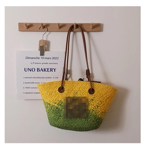 Detail of yellow and green straw tote bag showing hand-woven texture and leather strap