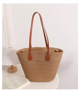 Detail of hand-woven straw tote bag with brown leather handles and soft fabric lining