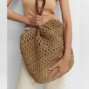 Handwoven straw tote bag with hollow floral pattern and dark brown leather straps