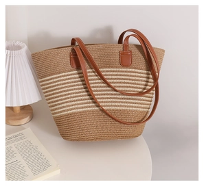 Detail of a woven straw tote bag with brown leather handles and striped texture