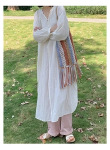 Detail of colorful woven shoulder bag with long tassels on green grass background