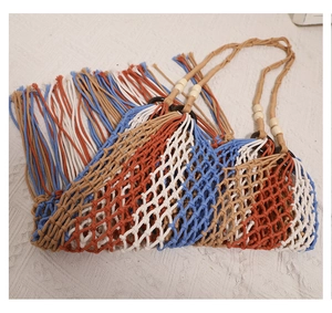 Detail of bohemian woven bag featuring tricolor cotton rope, long tassels, and wood beads