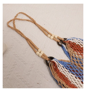 Detail of bohemian woven beach bag with colorful cotton ropes and beaded handle rings