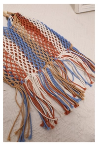 Detail of bohemian handwoven cotton bag with colorful tassels in orange and blue
