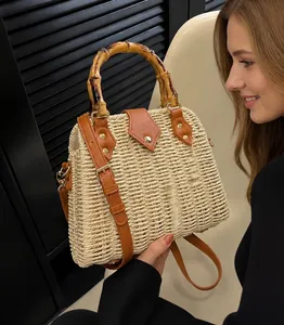 Détail d'un sac à main en paille tressée avec poignée en bambou et fermoir en cuir brun