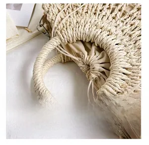Detail view of woven straw handbag featuring ring handles and beige drawstring liner