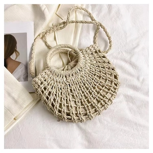 Detail of hollow-out beige straw bag with circular handle and woven crossbody strap