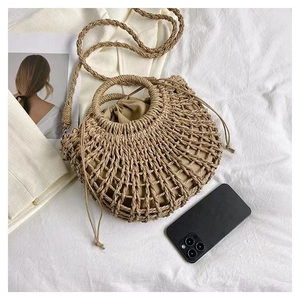 Flat lay of straw handbag with inner drawstring pouch and long braided shoulder strap