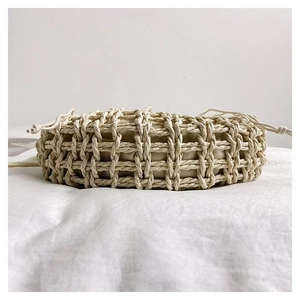 Detail of hollow woven straw bag featuring a cream cotton drawstring inner lining