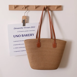 Minimalist straw tote bag with brown leather straps and hand-woven texture for beach use