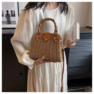 Détail du sac en paille tressée avec poignée en bambou et rabat en cuir marron