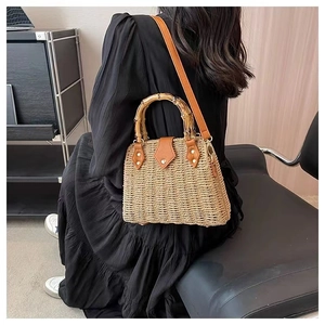 Détail du sac à main en paille tressée avec anses en bambou et bandoulière en cuir brun