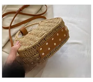 Detail of straw crossbody bag base with reinforced brown leather and metal rivets