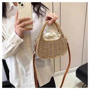 Detail of straw woven handbag with white drawstring lining and brown leather shoulder strap