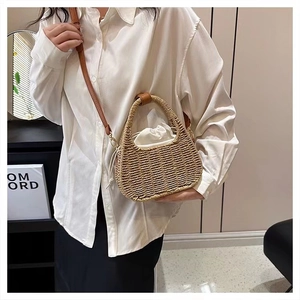 Close-up of handmade straw woven bag with brown leather straps and white drawstring liner