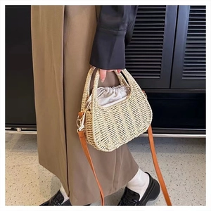 Detailed view of woven straw crossbody bag featuring cream drawstring liner and leather strap