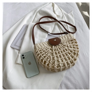 Detail of hollow-out straw bag with brown leather flap and secure silver snap button
