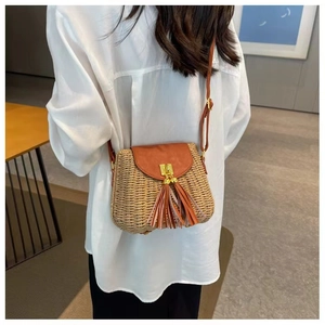 Detail of vintage straw crossbody bag featuring brown leather flap and long tassels