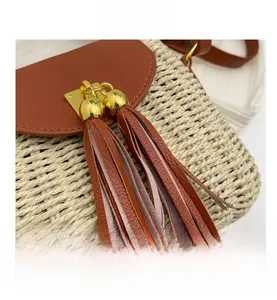 Detail of hand-woven straw bag with brown leather tassels and gold metal hardware