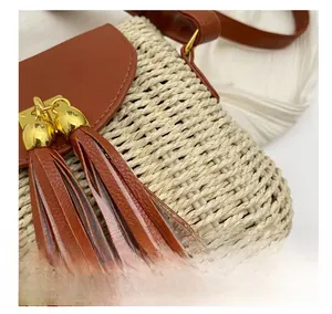 Detailed close-up of woven straw bag featuring brown leather trim and gold metal buckle