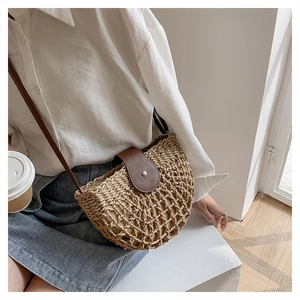 Detailed texture of the woven straw bag with premium brown leather flap and metal buckle