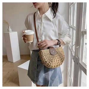Detailed close-up of straw crossbody bag featuring woven hollow pattern and brown leather flap