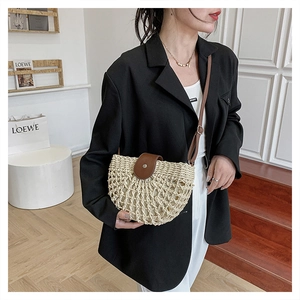 Close-up of beige woven straw shoulder bag with dark brown leather flap and strap