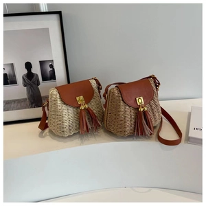 Detail view of woven straw crossbody bags with brown leather flap and tassel ornament
