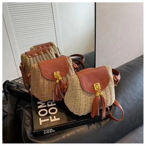 Detail of straw crossbody bag with brown leather flap and golden buckle tassel