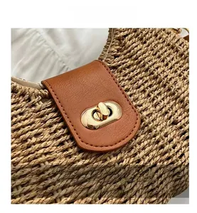 Detail showing golden metal twist lock on a brown woven straw bag with leather flap