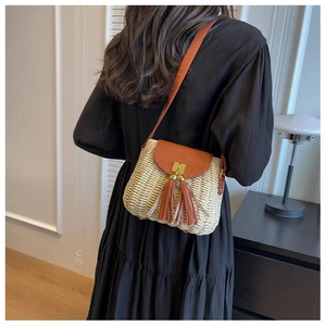 Detail of straw crossbody bag with brown leather fringe and gold metallic lock