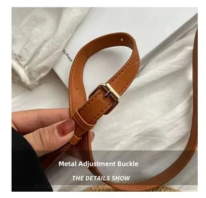 Detail of adjustable brown leather shoulder strap with light gold metal buckle hardware