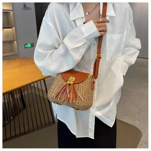 Detail of vintage woven straw crossbody bag with brown leather flap and long tassels