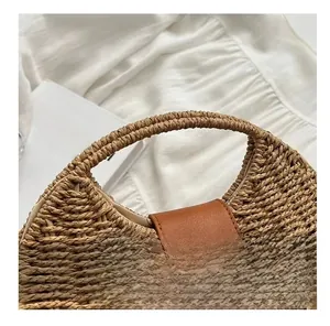 Detail of hand-woven straw bag featuring a brown leather flap and golden twist lock closure