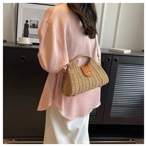 Detail of straw shoulder bag with brown leather flap and golden metal twist lock closure