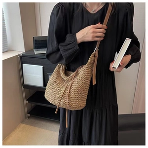 Detailed cross-weave texture of a crescent straw crossbody bag with brown leather strap