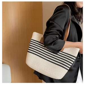 Close-up of striped woven straw tote bag with brown leather straps worn by a model
