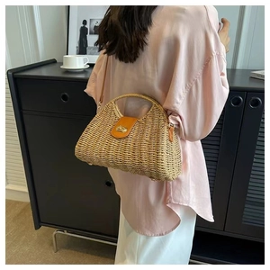 Close-up of woven straw bag with leather flap and metallic twist lock detail