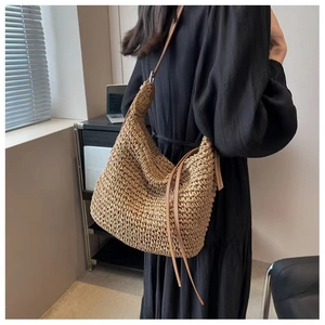 U-shaped paper rope woven bag with brown leather strap and long fringe tassel detail