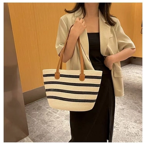 Detail of striped woven cotton tote bag featuring brown leather handles and casual style