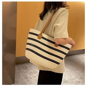 Detail of striped cotton woven tote bag with brown leather shoulder straps on model