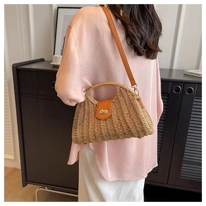 Detail of woven straw handbag with brown leather strap and gold rotating metal lock closure