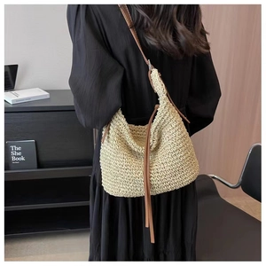 Detail of paper rope woven crossbody bag with brown leather strap and crescent shape
