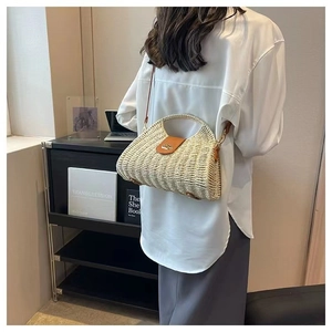 Detail view of woven straw shoulder bag with brown leather flap and gold metal clasp