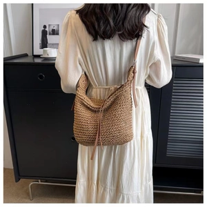 Detailed texture of brown woven paper rope shoulder bag with slim leather straps