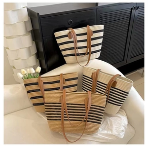 Detail of four striped woven tote bags with leather handles on a minimalist sofa
