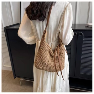 Detail of woven straw hobo bag with long leather tassels and a sleek shoulder strap