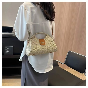 Detail of cream straw half-moon bag with brown leather flap and metal clasp on model